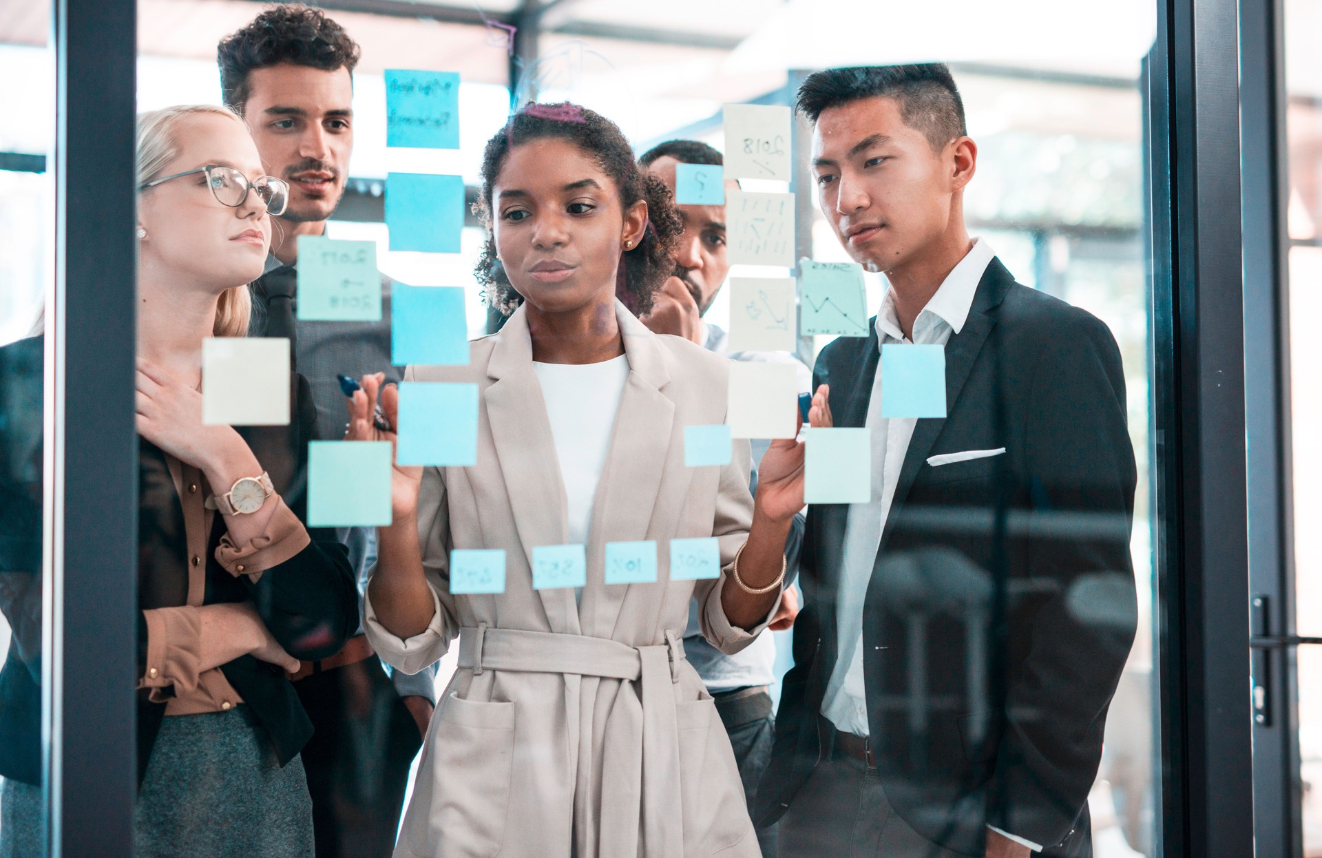 Diverse Team Collaborating on a Project Plan Using Sticky Notes in a Modern Office Setting